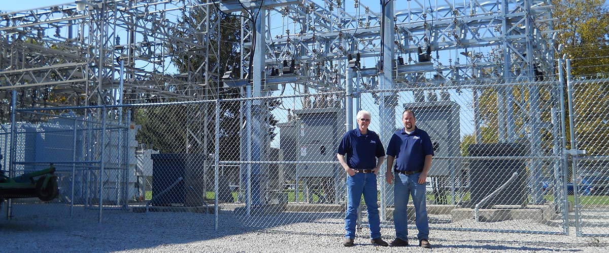 Mike and Matt Pals standing in front of an electric sub station