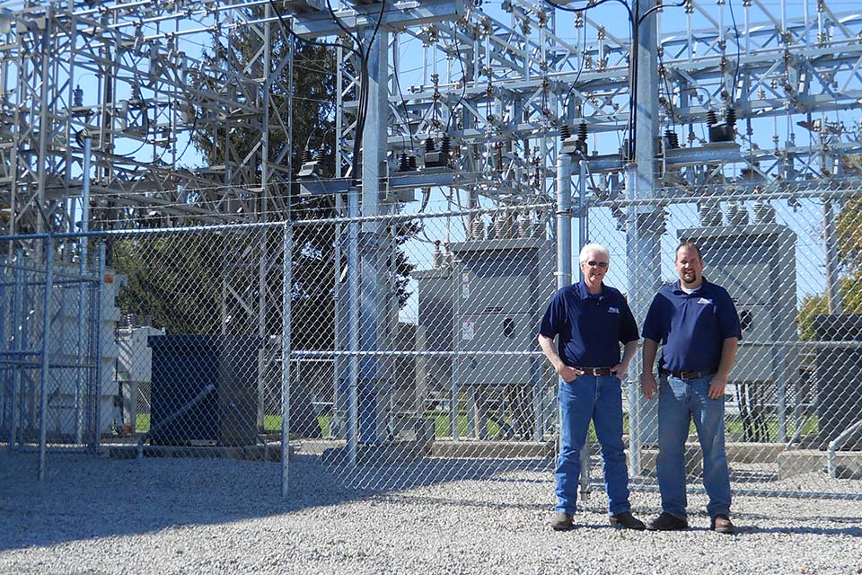 Mike Pals and Matt Pals standing in front of an electrical sub station