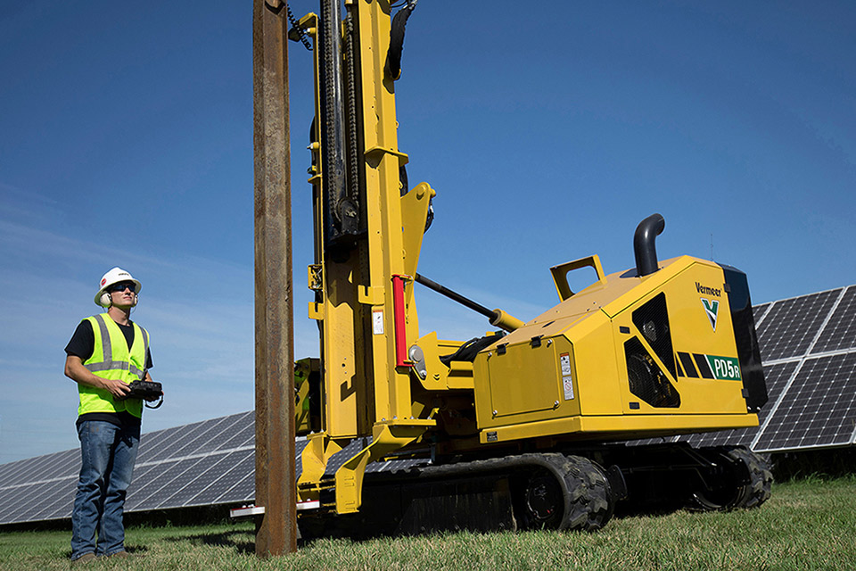 Pals Electric employee remotely running a solar pile driving machine