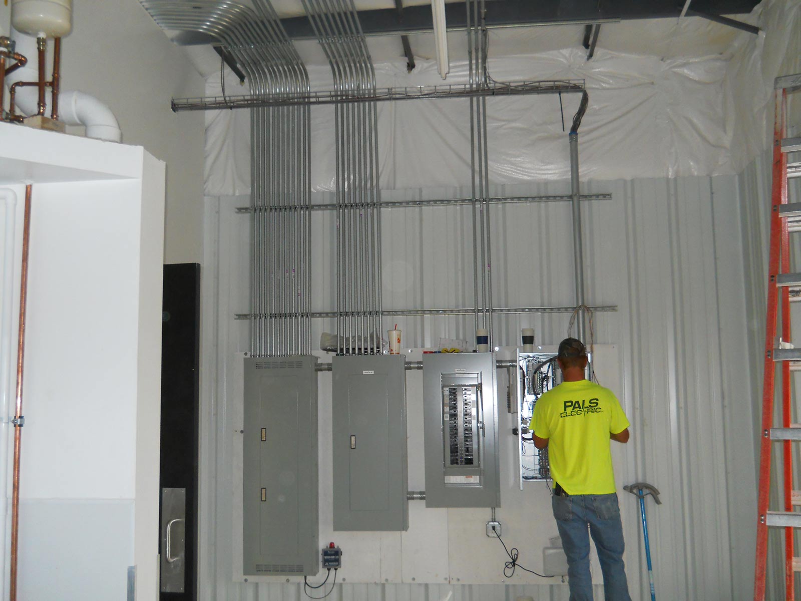 Pals Electric electrician working in a service panel at a commercial building