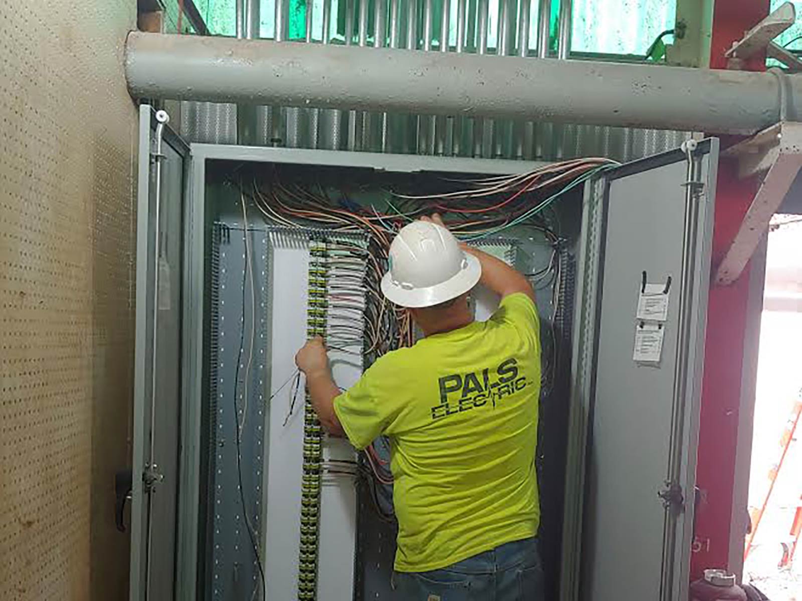Pals Electric electrician working in a service panel at an industrial or manufacturing facility