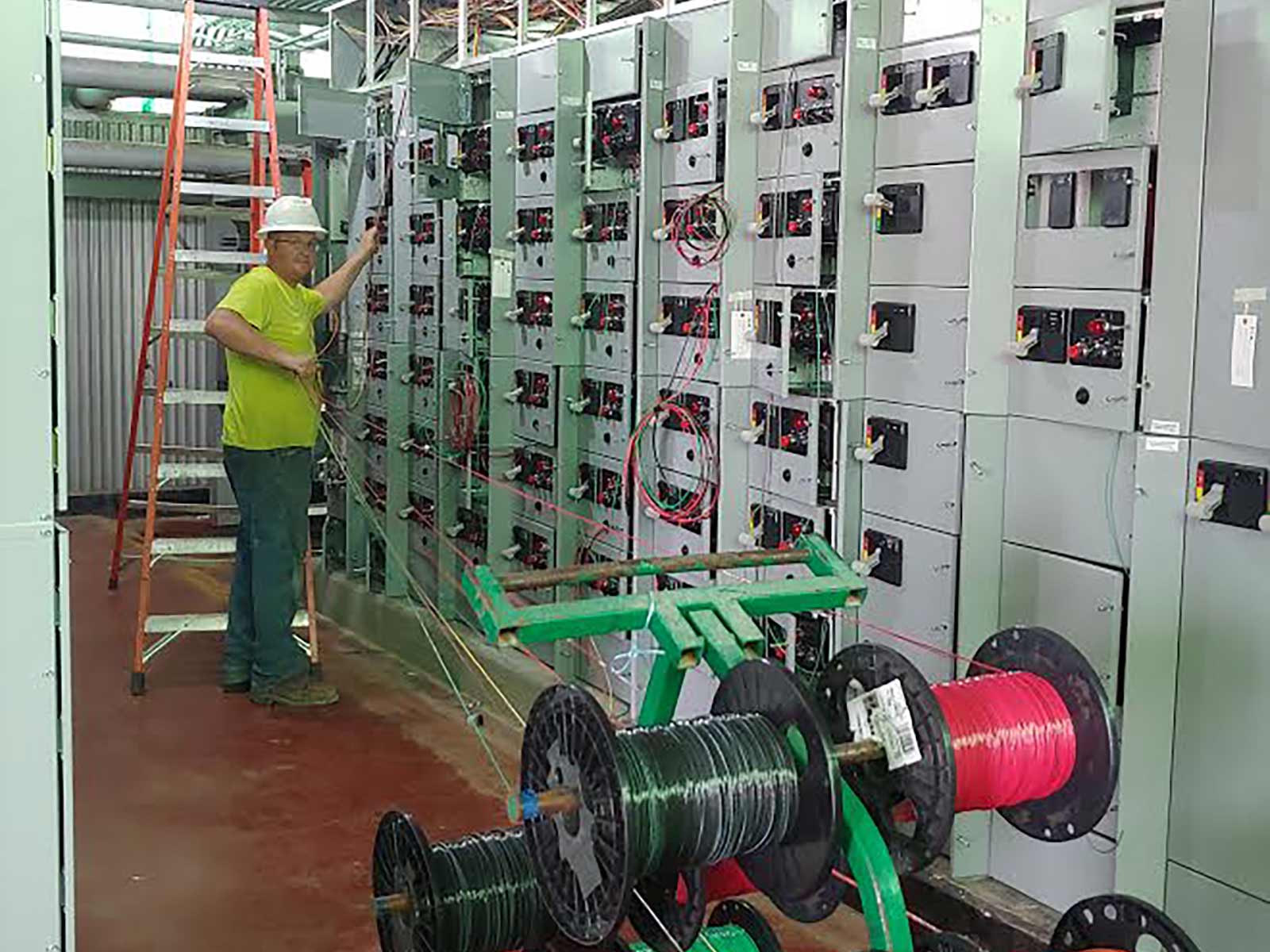 Pals Electric electrician pulling wire from a spool at an industrial manufacturing facility