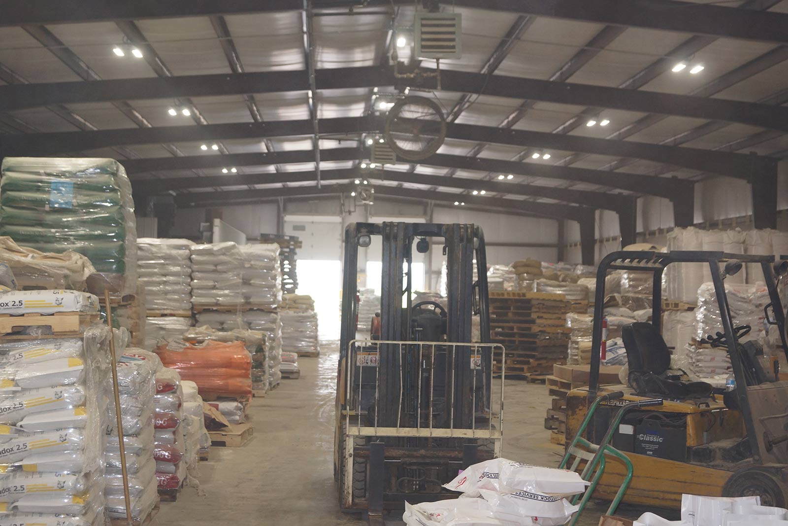 interior view of an Effingham feed mill showing lighting fixtures, forklifts, and pallets of bags